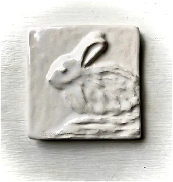 Relief sculpture of a sitting rabbit on a textured ceramic tile, highlighting the artistry in animal-themed decor.